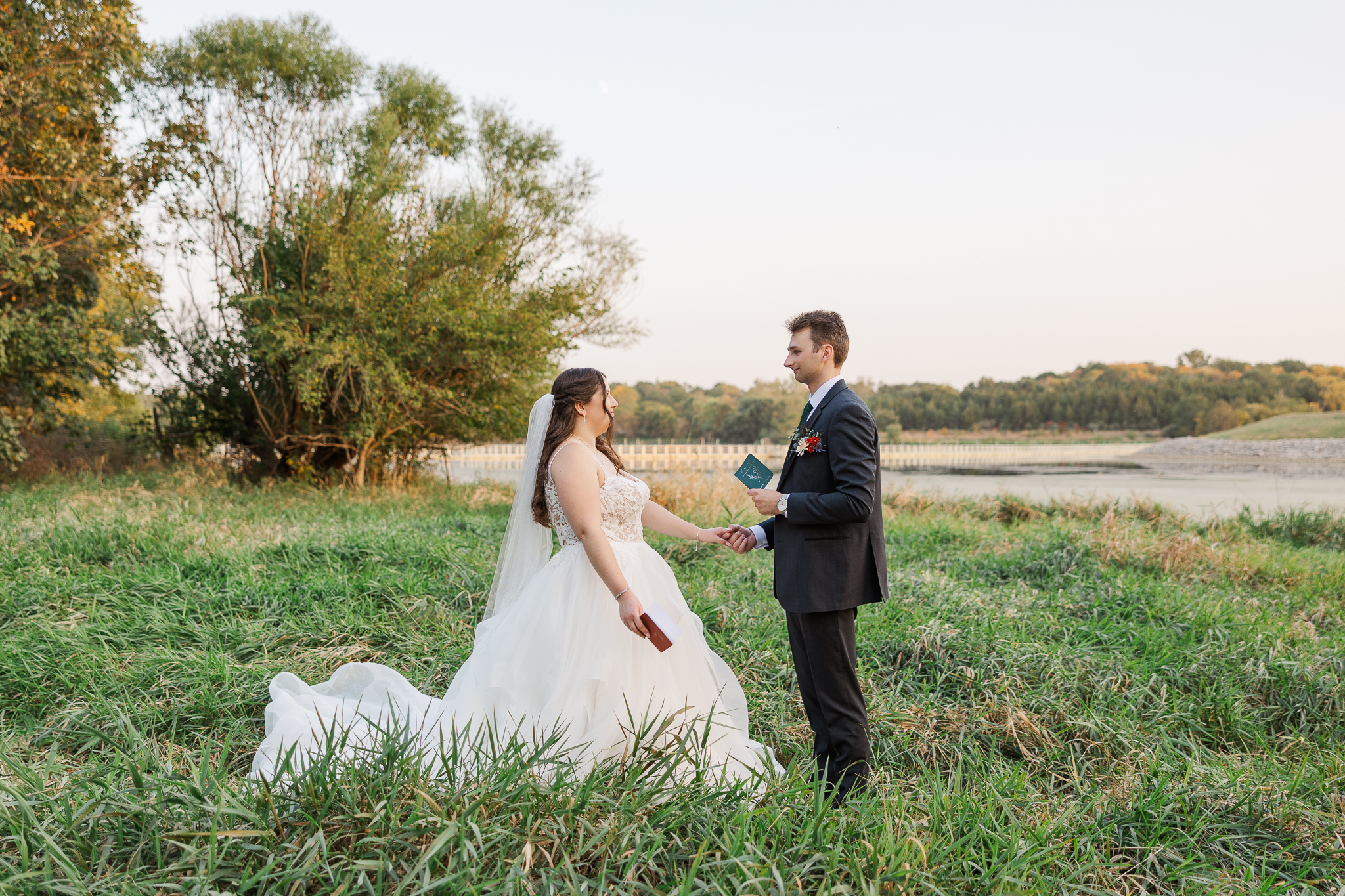 A bride and groom exchanging private vows at Standing Bear Lake as part of their first look on their wedding day.