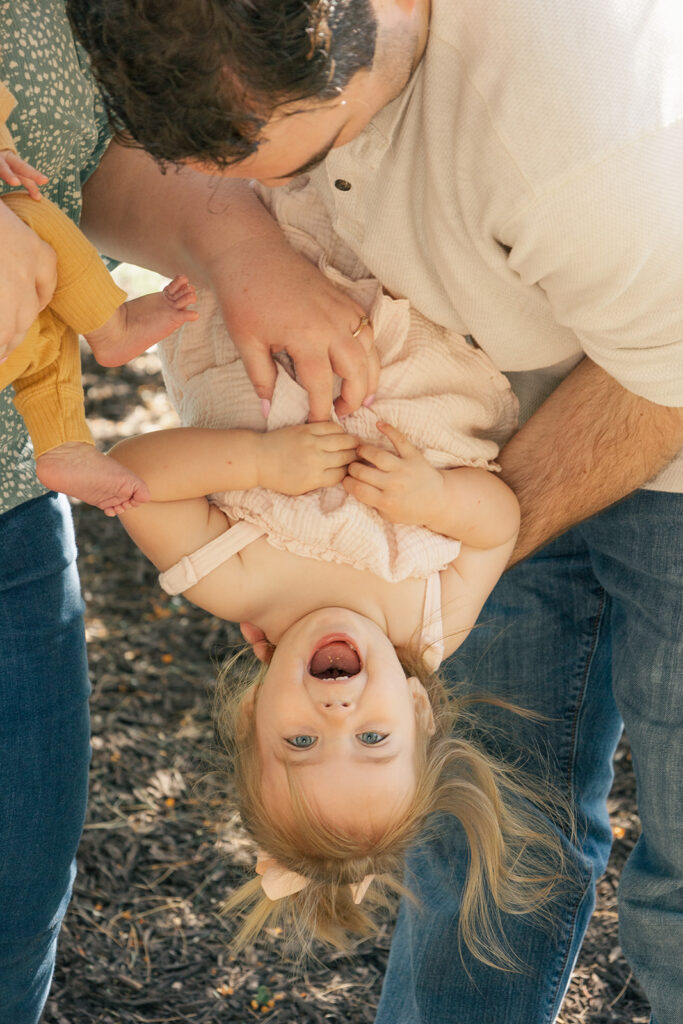 Spring family photos with parents, a newborn, and a toddler at Omaha's OPPD Arboretum surrounded by blooming flowers.