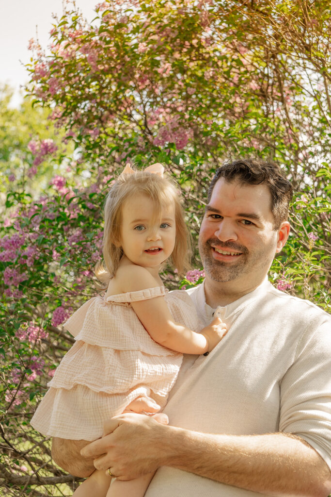 Spring family photos with parents, a newborn, and a toddler at Omaha's OPPD Arboretum surrounded by blooming flowers.