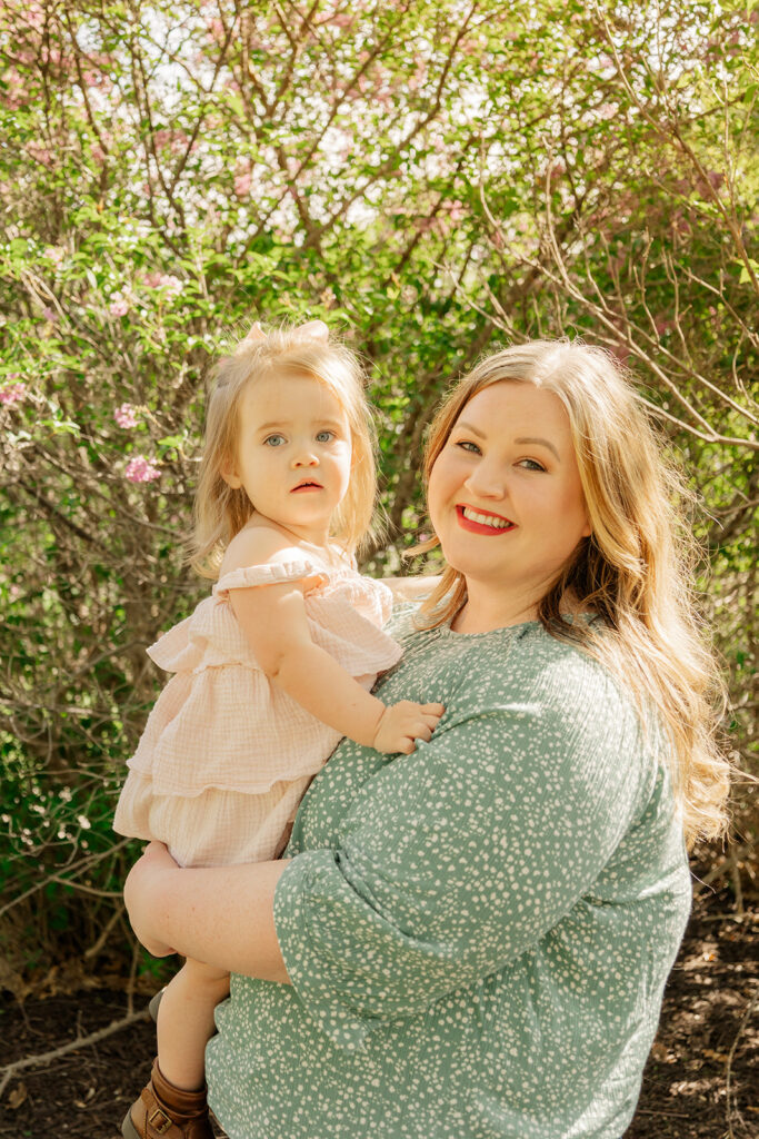 Spring family photos with parents, a newborn, and a toddler at Omaha's OPPD Arboretum surrounded by blooming flowers.