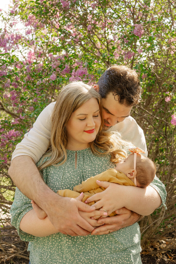 Spring family photos with parents, a newborn, and a toddler at Omaha's OPPD Arboretum surrounded by blooming flowers.